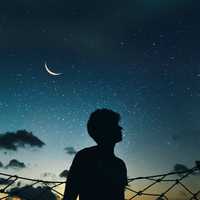 Silhouette of boy looking up at the sky of stars