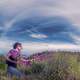 woman-picking-purple-flowers-under-the-clouds-and-sky