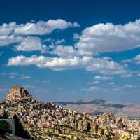 Landscape with houses in stones under sky and clouds in Cappadocia, Turkey