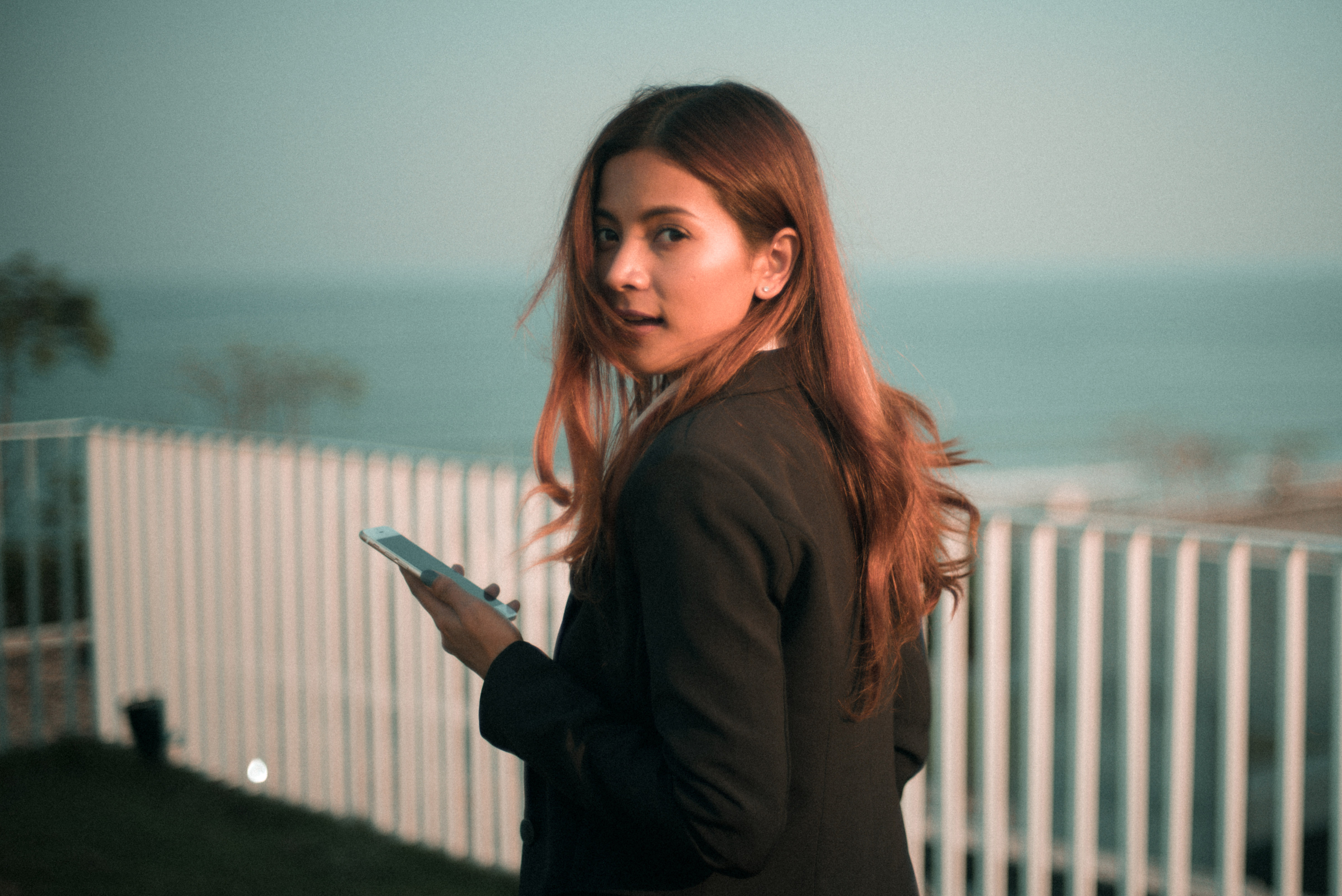 Woman looking back at camera holding a smartphone Image Free Stock 